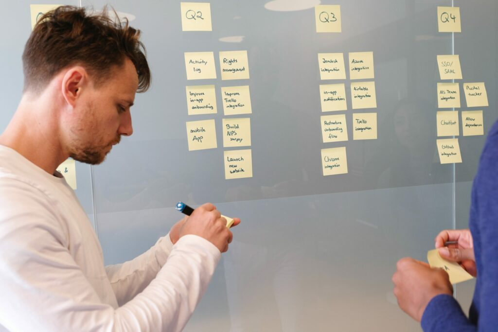 Two men standing in front of a glass surface creating goals using sticky notes