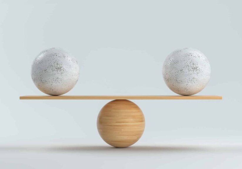 wooden scale balancing two big balls in front white background