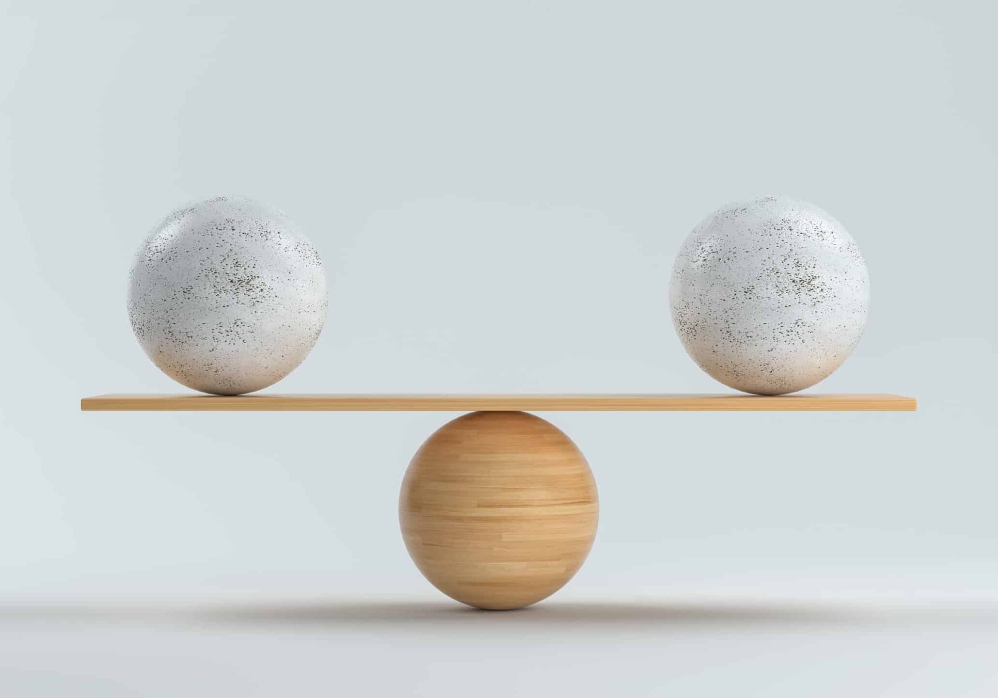 wooden scale balancing two big balls in front white background