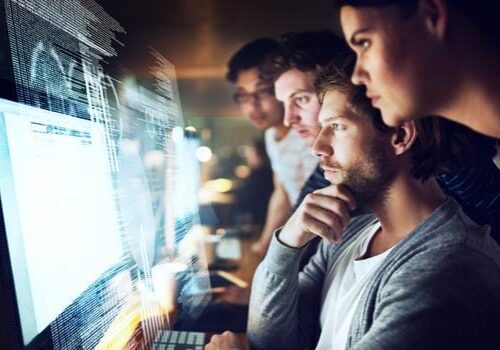 Shot of a group of programmers working on a computer code at night