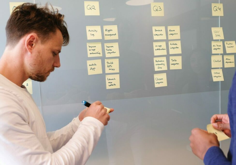 Two men standing in front of a glass surface creating goals using sticky notes